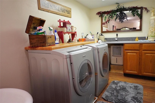 laundry room featuring washing machine and clothes dryer and light hardwood / wood-style flooring