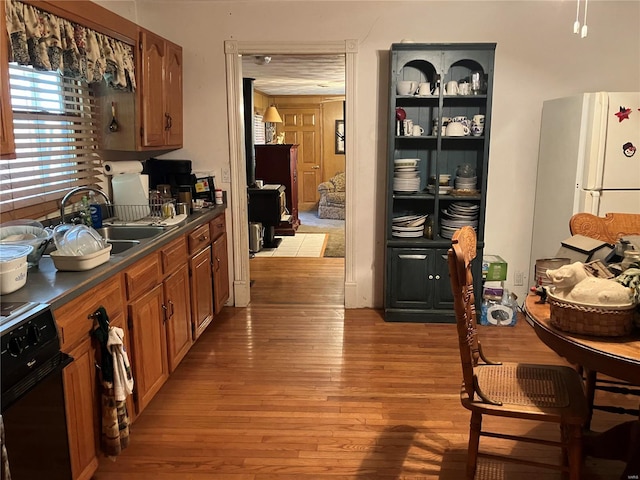 kitchen with wood-type flooring, sink, white refrigerator, and oven