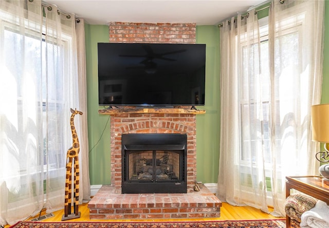 living room featuring hardwood / wood-style flooring, a brick fireplace, and brick wall