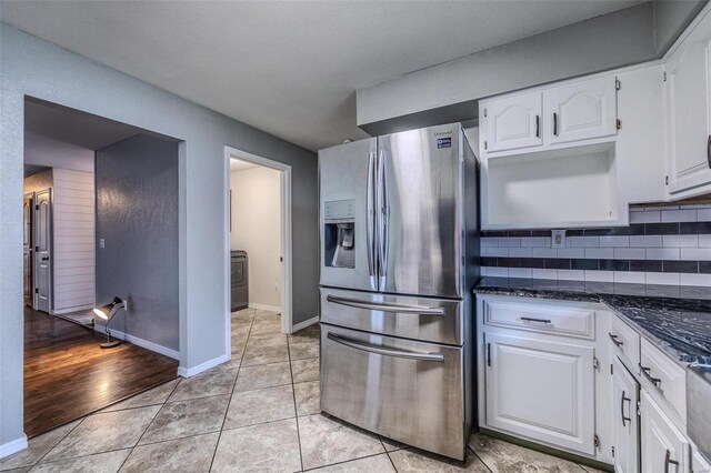 kitchen with white cabinetry, dark stone countertops, stainless steel fridge, light hardwood / wood-style flooring, and backsplash