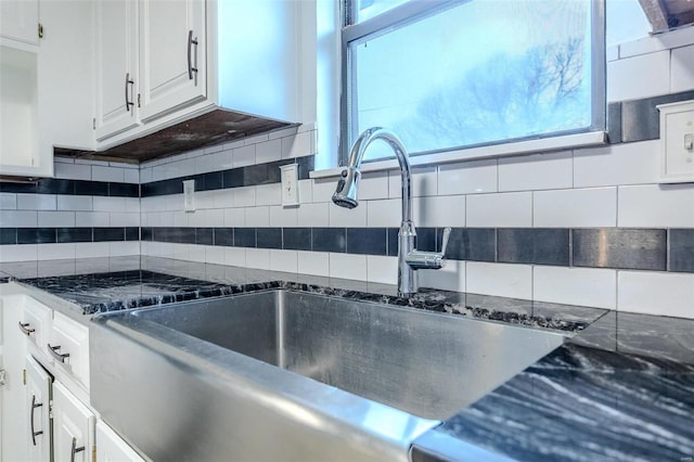 kitchen with tasteful backsplash, sink, dark stone countertops, and white cabinets