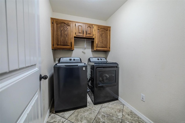 laundry room with washer and clothes dryer, cabinets, and light tile flooring