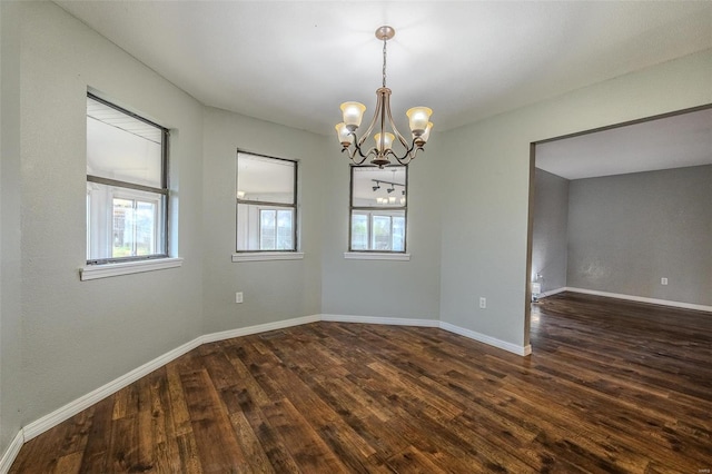 spare room featuring dark hardwood / wood-style flooring and a chandelier