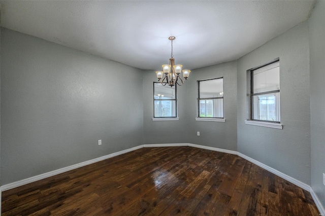 unfurnished room featuring dark wood-type flooring and a chandelier