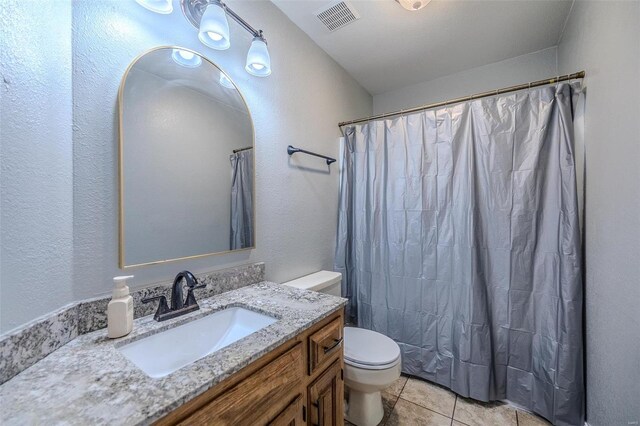 bathroom featuring tile flooring, toilet, and vanity with extensive cabinet space