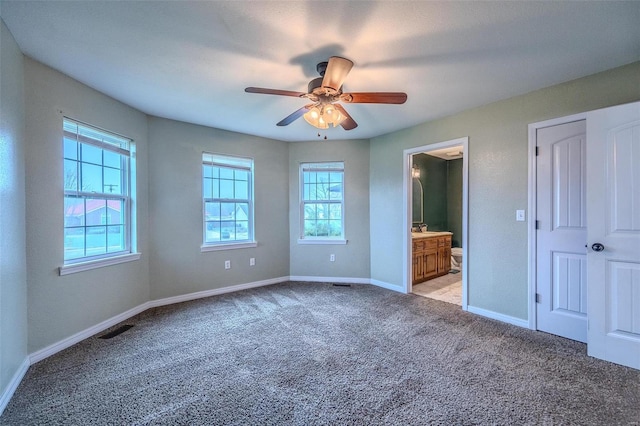 unfurnished bedroom with ensuite bathroom, light carpet, and ceiling fan