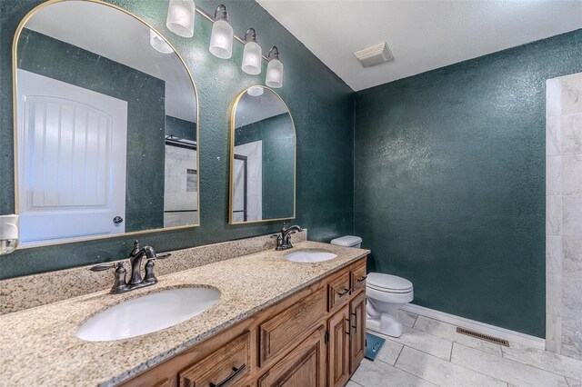 bathroom featuring tile floors, dual bowl vanity, and toilet