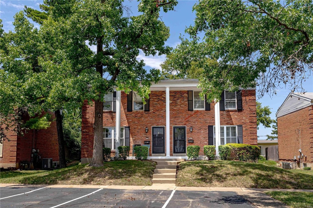 view of front of property with central AC and a front lawn