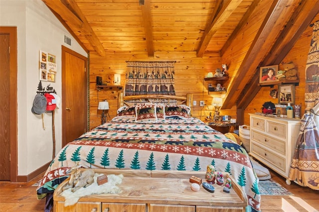 bedroom with visible vents, lofted ceiling with beams, wood ceiling, wooden walls, and wood finished floors