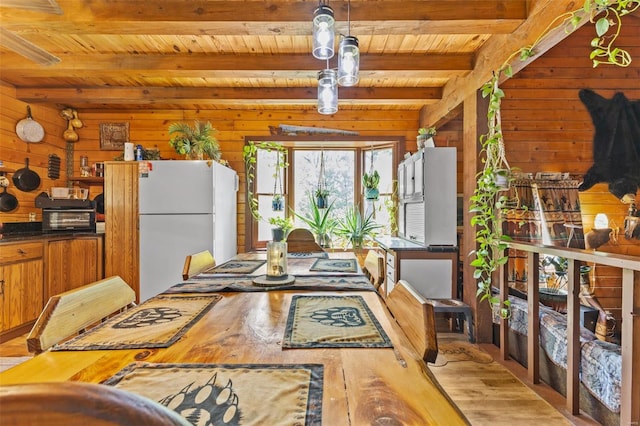 dining space featuring wood ceiling, light wood finished floors, beam ceiling, and wooden walls