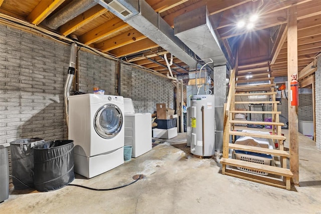 unfinished basement featuring water heater, brick wall, and washer and dryer