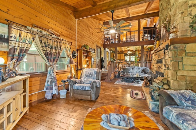 living room with wooden ceiling, wood walls, a ceiling fan, beam ceiling, and hardwood / wood-style floors