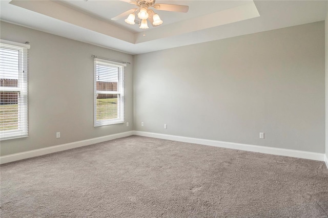 carpeted empty room with a tray ceiling and ceiling fan