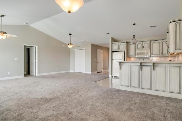 kitchen with backsplash, white appliances, light colored carpet, vaulted ceiling, and ceiling fan