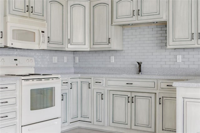 kitchen featuring light stone countertops, white appliances, and tasteful backsplash