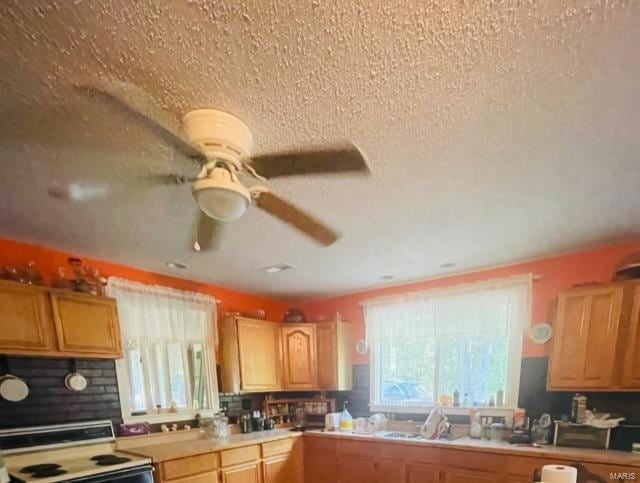 kitchen featuring range, backsplash, a textured ceiling, and ceiling fan