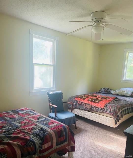 carpeted bedroom with a textured ceiling and ceiling fan