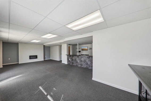 basement with dark colored carpet, a fireplace, and a paneled ceiling