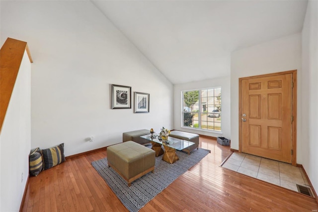 living room with high vaulted ceiling and light hardwood / wood-style floors