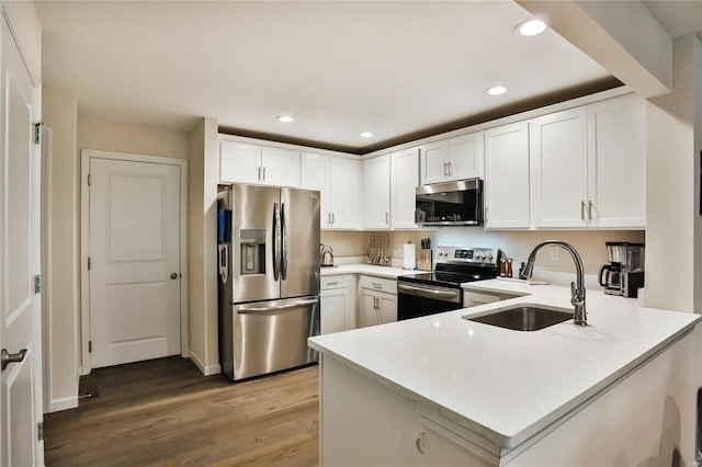 kitchen featuring appliances with stainless steel finishes, sink, kitchen peninsula, light hardwood / wood-style floors, and white cabinetry