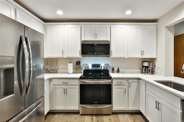 kitchen with sink, white cabinetry, light wood-type flooring, and stainless steel appliances