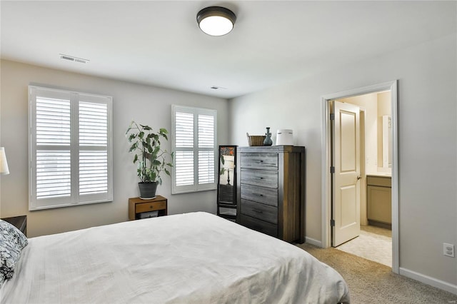 bedroom with light carpet and ensuite bathroom