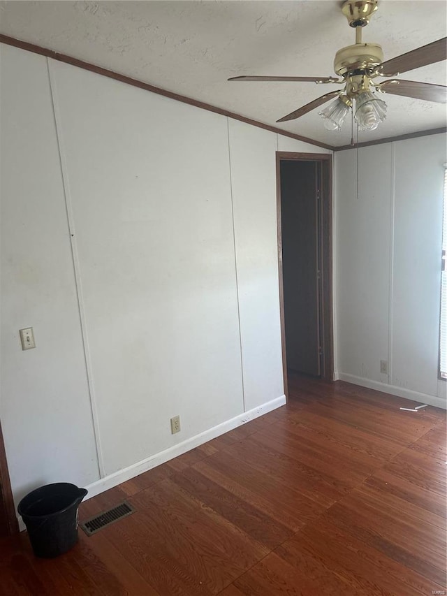 empty room with a textured ceiling, ornamental molding, dark hardwood / wood-style floors, and ceiling fan