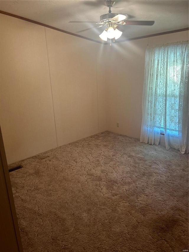 spare room featuring carpet, crown molding, and ceiling fan