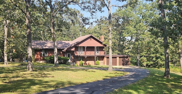 view of front facade featuring a balcony, a front lawn, and a garage