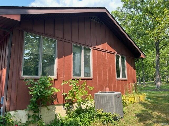 view of side of home with central air condition unit and a lawn