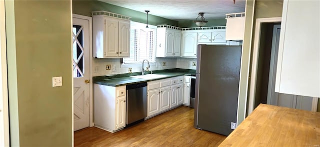 kitchen with decorative backsplash, stainless steel appliances, sink, white cabinets, and light hardwood / wood-style floors