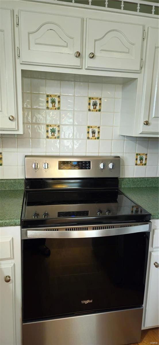 kitchen featuring white cabinets, decorative backsplash, and electric stove