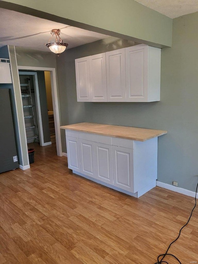 kitchen with white cabinetry, a textured ceiling, and light hardwood / wood-style flooring