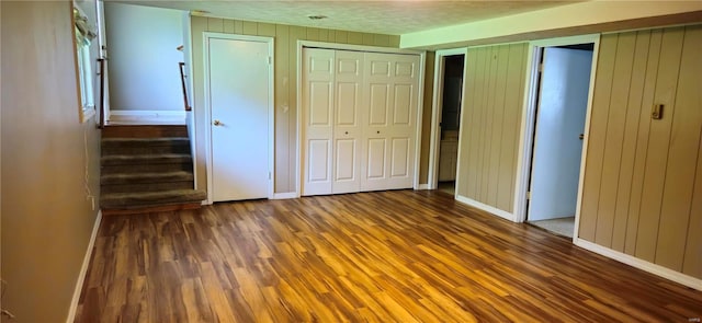 unfurnished bedroom with dark hardwood / wood-style flooring and wooden walls