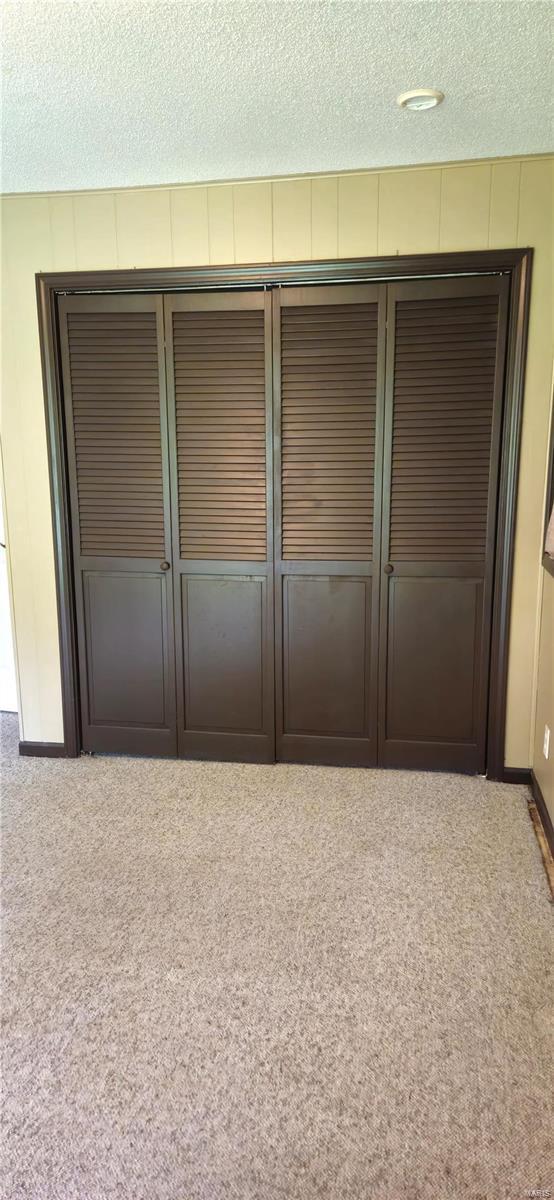 unfurnished bedroom featuring a textured ceiling, light colored carpet, and a closet