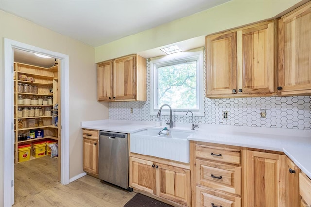 kitchen with light countertops, light brown cabinets, dishwasher, and a sink