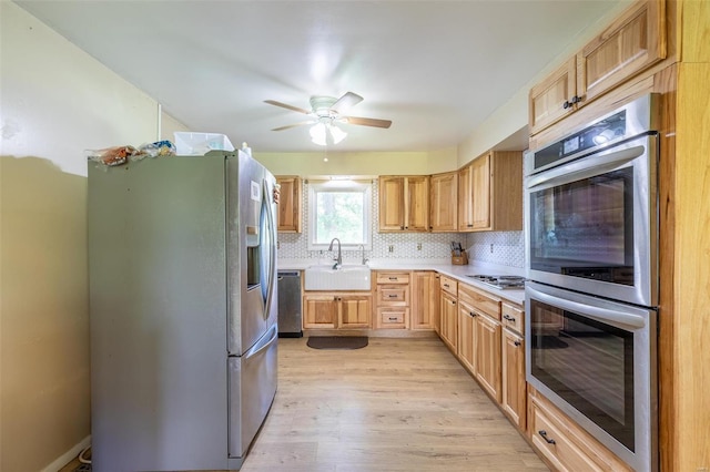 kitchen featuring tasteful backsplash, light countertops, appliances with stainless steel finishes, light wood-style floors, and a sink