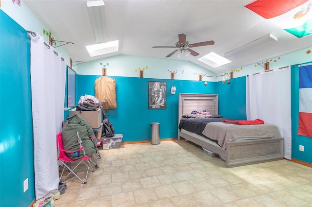 bedroom with ceiling fan, lofted ceiling with skylight, and baseboards