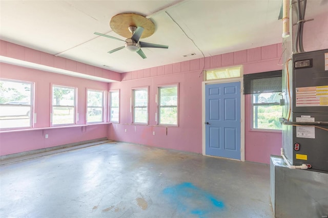 unfurnished sunroom featuring heating unit, plenty of natural light, visible vents, and ceiling fan