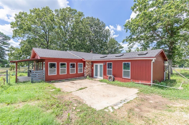 view of front of property featuring driveway, fence, a patio, and french doors