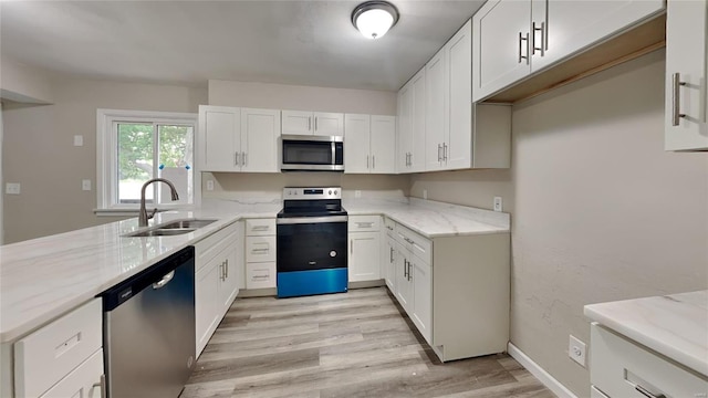 kitchen featuring light stone countertops, appliances with stainless steel finishes, sink, light hardwood / wood-style flooring, and white cabinets