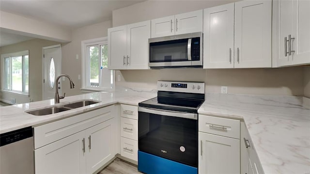 kitchen featuring white cabinets, sink, light stone countertops, and stainless steel appliances