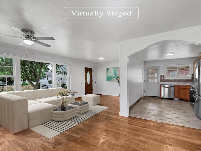 living room with light hardwood / wood-style floors, ceiling fan, crown molding, and sink