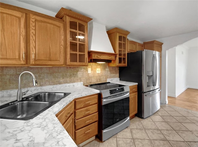 kitchen featuring appliances with stainless steel finishes, backsplash, custom exhaust hood, sink, and light tile patterned floors