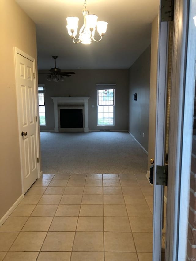 hall with an inviting chandelier, plenty of natural light, and light tile patterned flooring