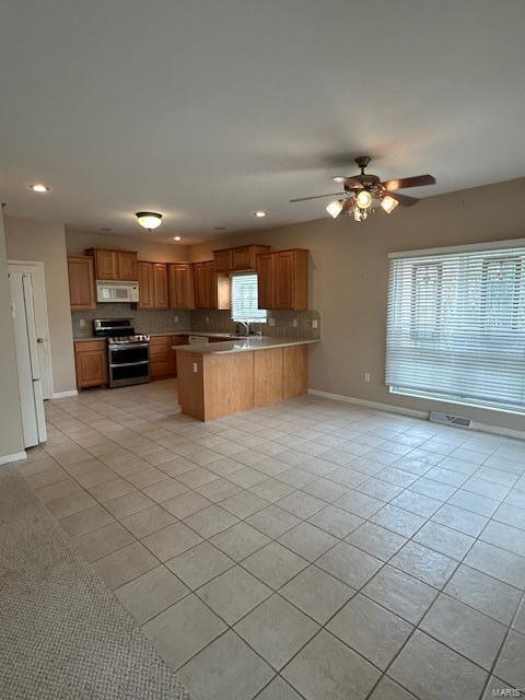 kitchen with double oven range, backsplash, kitchen peninsula, light tile patterned flooring, and ceiling fan