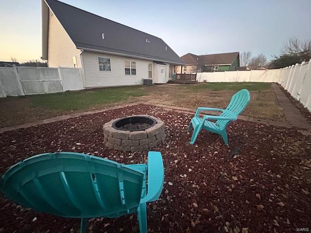 yard at dusk with cooling unit and a fire pit