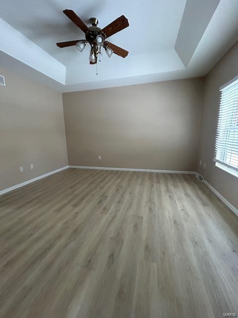 unfurnished room with hardwood / wood-style flooring, ceiling fan, and a raised ceiling