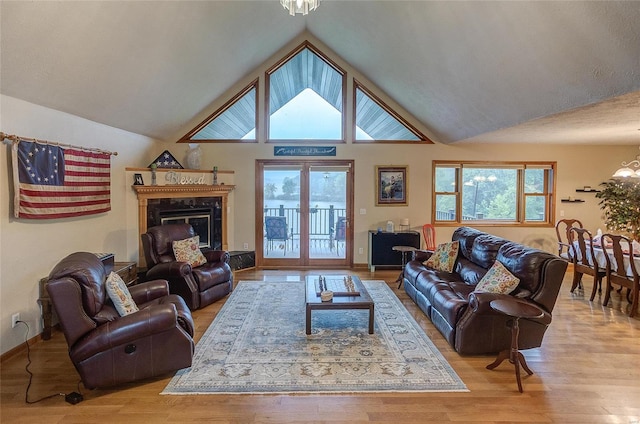 living room featuring french doors, a fireplace, light hardwood / wood-style flooring, and vaulted ceiling