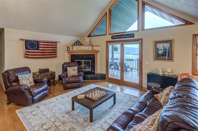 living room with a high end fireplace, light wood-type flooring, and high vaulted ceiling